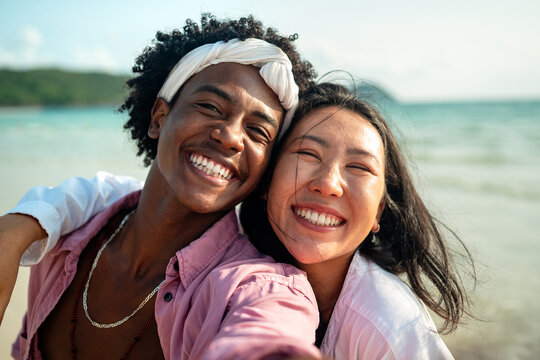 Happy couple having fun at the beach, playing and laughing together in a romantic tropical setting