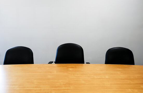 Rang&eacute;e de chaises noires dans une salle de r&eacute;union sur fond de mur blanc. Salle de conf&eacute;rence.