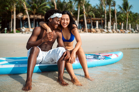 Diverse pair of friends, couple laughing together in a scenic coastal environment