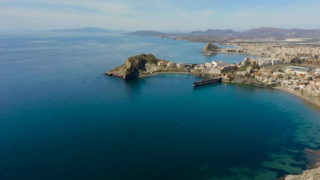 Aerial view of Aguilas city in Murcia, Spain, featuring Levante Bay and marina. Coastal urban landscape with calm Mediterranean waters, harbor structures and scenic shoreline.