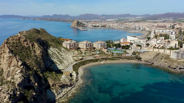 Aerial view of Aguilas city in Murcia, Spain, featuring Levante Bay and marina. Coastal urban landscape with calm Mediterranean waters, harbor structures and scenic shoreline.