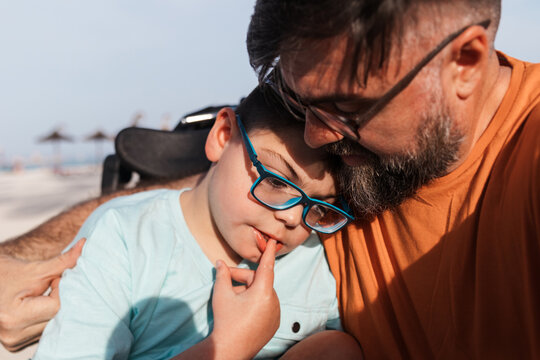 Father and son embracing at beach, celebrating disability