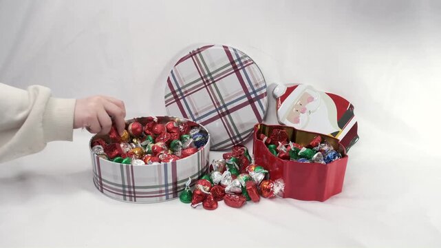 Two young girls reaching in for a handful of brightly wrapped Christmas candy.
