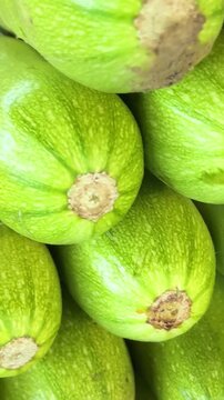 Natural zucchini squash stacked in market display with fresh green texture and healthy farm vegetable concept for organic food shopping.