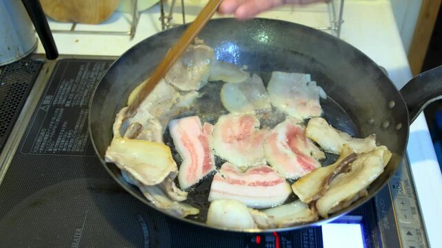直径32cmの大型鉄フライパンで焼き肉用の豚バラ肉を炒め、菜箸で裏返すシーン