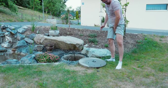 Man experiencing sudden groin pain after lifting a heavy manhole cover. Workplace safety concept of heavy lifting, muscle strain, possible hernia, and occupational injury.
