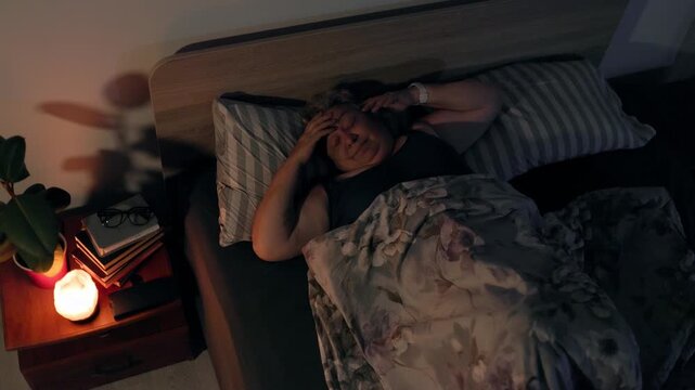 Overweight Tired Elderly Lady Waking Up with Bad Headache in Dark Bedroom