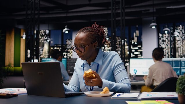 Stressed businesswoman dealing with eating disorder during late night work session, temptation.