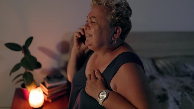 Overweight Elderly Woman With Heart Pain Making Emergency Phone Call In Bed