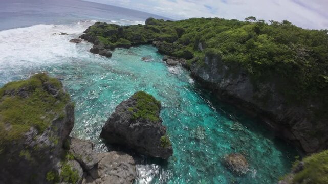 Drone flight along the volcanic coastline of Niue with turquoise natural pools