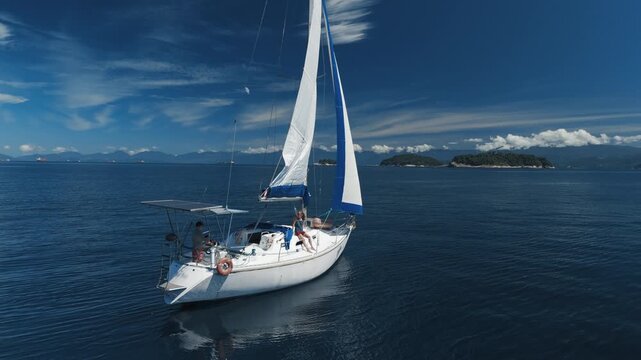Sailing boat moves in the tropical sea near the Brazilian shore during nice sunny day. Couple sailing the small sailing yacht in the sea. Aerial drone shot of the sailing boat