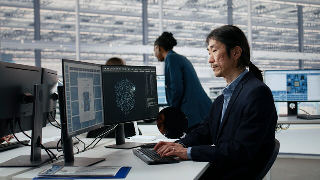 Asian man using AI in microchip factory office to optimize hardware, Senior manager training AI model in RD in research lab.