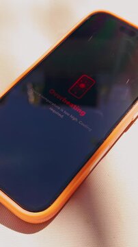 Vertical video. Smartphone Displaying Overheating Warning Under Direct Sunlight Near Swimming Pool, Mobile Technology And Summer Heat