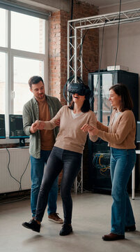 Team helping colleague experience virtual reality headset in industrial tech loft