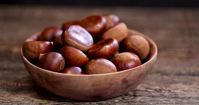 Edible harvested chestnuts, a group of large fresh chestnuts harvested and scattered on an old wooden table during cooking and cooking, food and drink