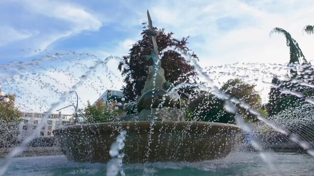 Low angle view of public park fountain with spraying water droplets