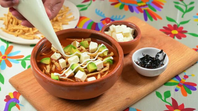 Close-up of preparing authentic Aztec soup with sour cream in a clay bowl