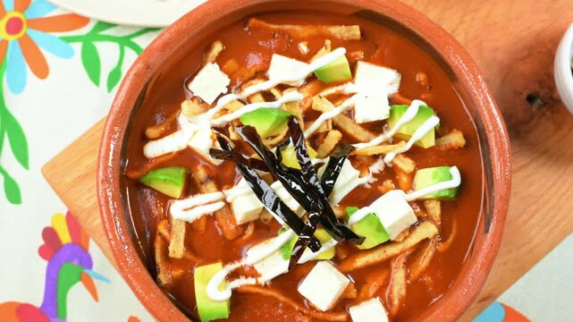 Traditional tortilla soup served in a clay bowl. Top camera slowly rotating
