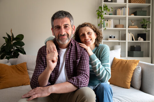 Middle aged couple sharing loving embrace on sofa