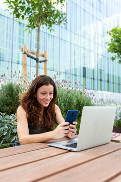 Remote worker woman telecommuting with laptop and smartphone