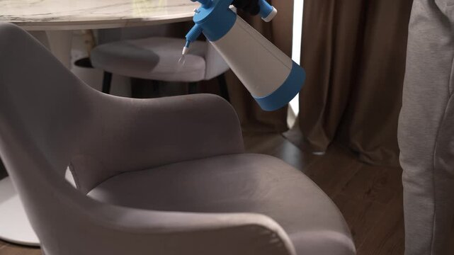 Chair fabric stain treatment with a manual pump sprayer shot in 4K. Cleaning service maintains textile furniture hygiene