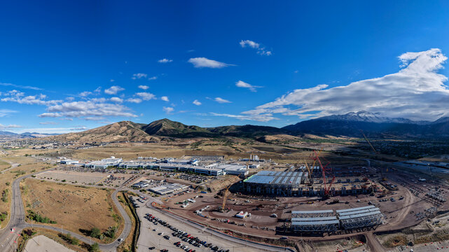 Aerial panorama of the Silicon Slopes construction project for a large factory in the Technology Corridor, with heavy machinery and steel framework in Lehi, Utah, United States.