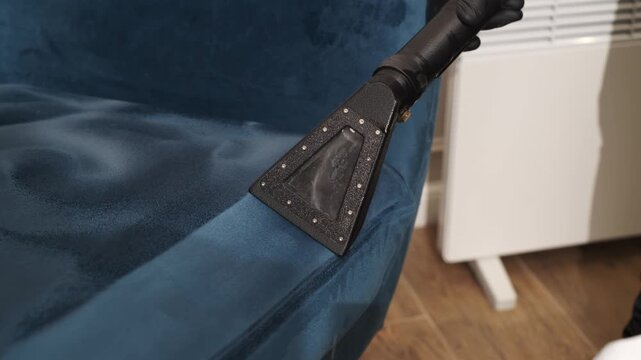 Velvet Chair Water Extraction Close-up. Water extraction cleaning on a blue velvet chair captured in 4K. Cleaning specialist pulls moisture from the upholstery seat