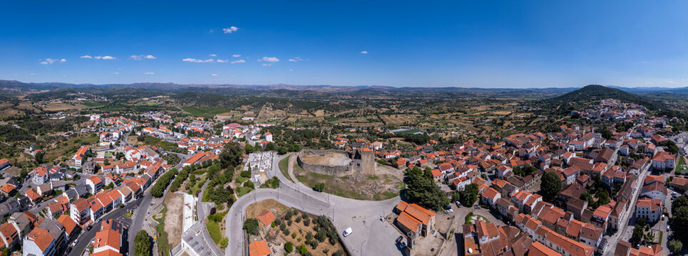 Aerial view of Belmonte Castle surrounded by historic red-tiled rooftops, winding streets, and the rolling landscape in Belmonte, Castelo Branco Distri, Portugal.