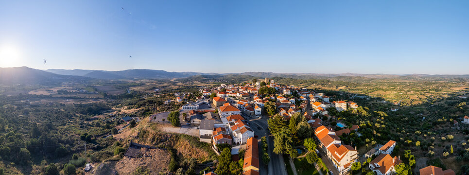 Aerial view of the historic town of Belmonte with terracotta rooftops, surrounded by rolling hills and lush landscape under a clear sky in Belmonte, Castelo Branco District, Portugal.
