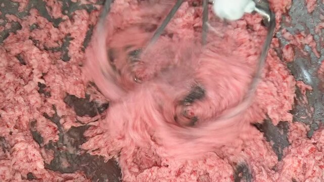 Electric mixer whips pink buttercream into a smooth fluffy consistency creating vibrant frosting for cake decorating pastry filling and professional baking preparation