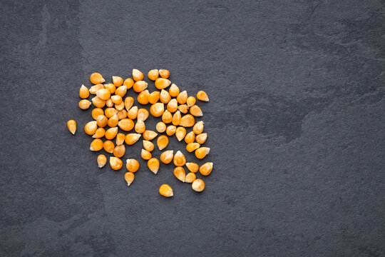 Popcorn kernels arranged on a dark surface, minimalist image ideal for culinary and ingredient concepts