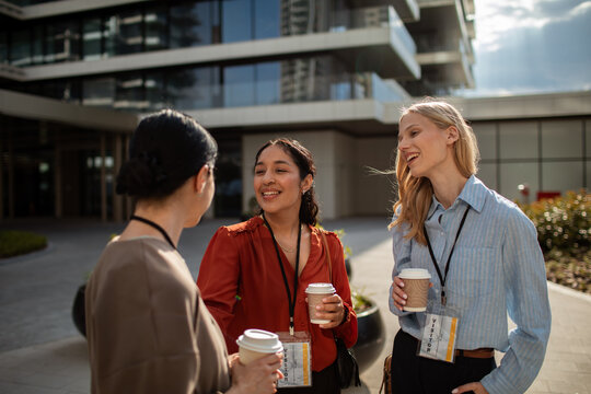 Three professionals networking with coffee outside modern office