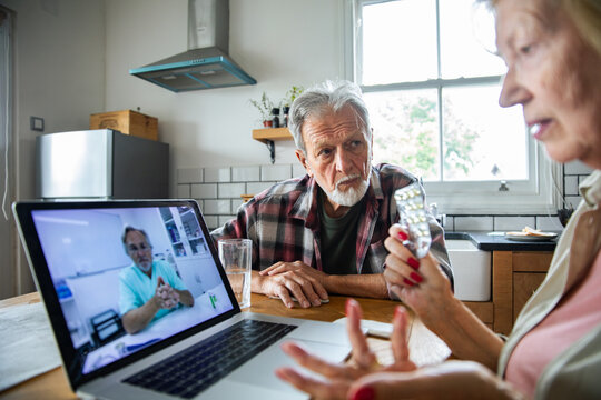 Senior couple discussing medication with doctor on video call at home
