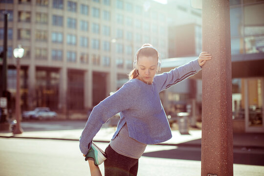 Young woman stretching with headphones on a city street
