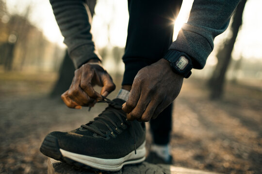 Runner tying shoelaces on park trail at sunrise
