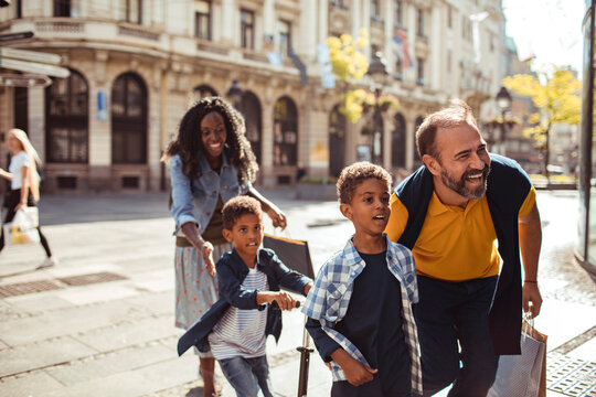 Happy family walking and shopping on sunny city street