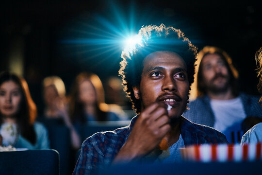 Young man watching a movie in a cinema with popcorn