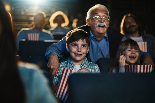 Grandfather and kids watching a movie at the cinema