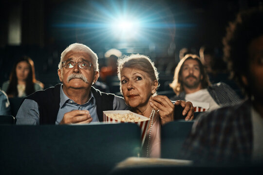 Senior couple watching a movie in a theater with popcorn
