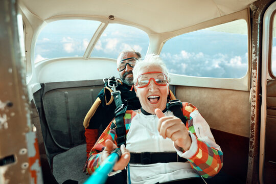 Happy senior couple taking skydiving selfie inside airplane