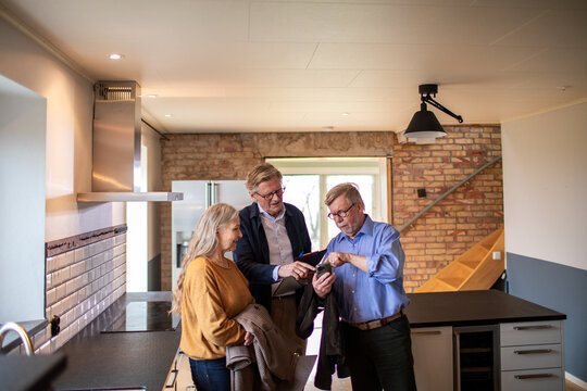 Senior couple touring home with real estate agent in modern kitchen