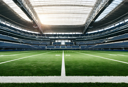 A football field, running from the centerline to the edge, is located within a large stadium featuring green grass.