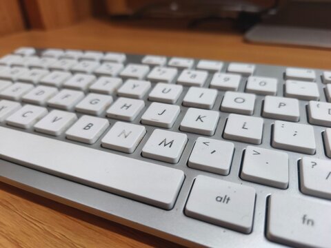 The image shows a silver computer keyboard with clean white square keys arranged neatly.