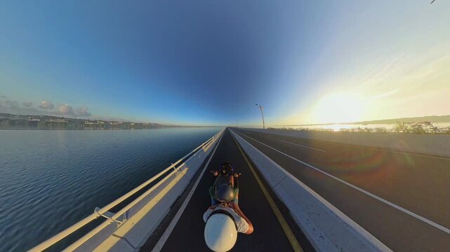 First Person Motorcycle Ride Along Southern Terminus of Bali Mandara Toll Road at Sunrise, Wide Angle Coastal Highway Above Calm Water and Golden Morning Light