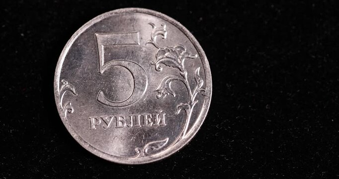 small-denomination Russian coins on a black surface, official money worth 5 rubles of the Russian Federation lies on a black surface, real currency