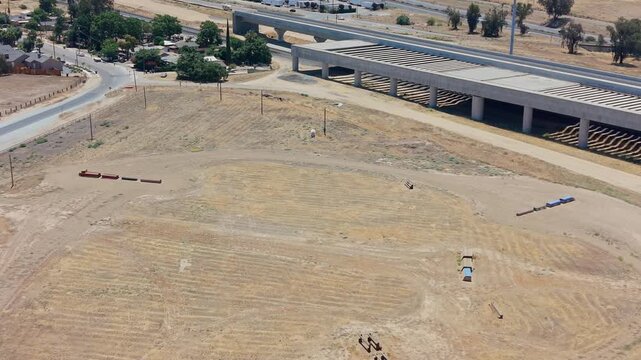 Reversing Aerial Drone Shot Over California High Speed Rail Construction With Overpass Freeway Traffic and Neighborhood