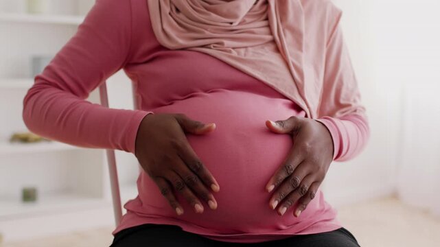 Joyful African American Woman In Pregnancy Touching Her Belly With Happiness At Home, Celebrating Maternity And Expectation. Feeling Love And Anticipation For New Life, Cozy Setting.