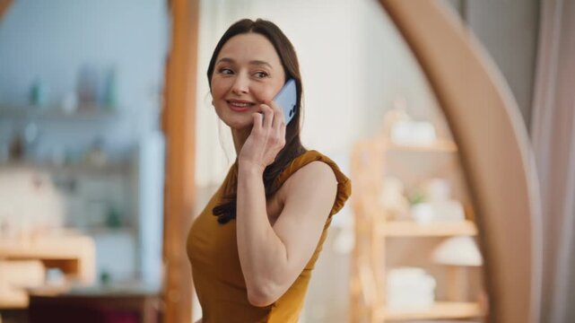 Happy brunette trying dress talking smartphone in home closeup. Smiling woman