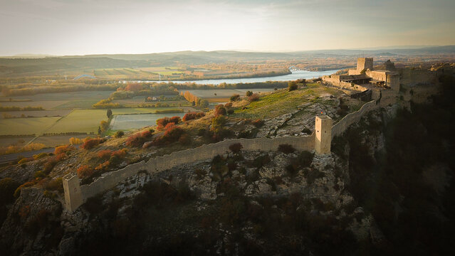 Aerial view of Fortress Mornas perched on a rocky cliff overlooking the Rhone valley with historic stone walls and autumn foliage in Mornas, Provence-Alpes-Cote d'Azur, France.
