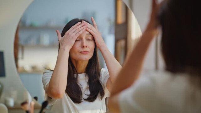 Lady applying anti-age cream on face performing morning beauty routine closeup. 